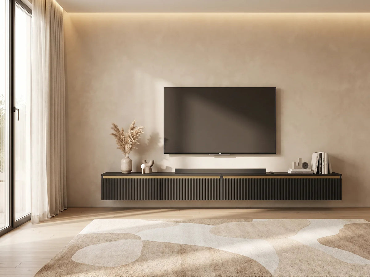 Meuble TV Suspendu Noir Mat Rainuré 280 cm SELENE dans un salon minimaliste lumineux aux tons chauds, vue de face